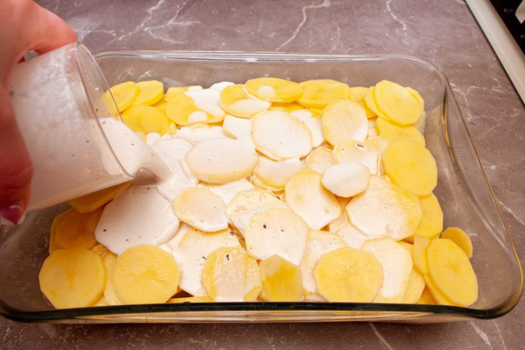 Фото. Выливаем на картофель в противне сливки. Французский катофель уже скоро будет готов.