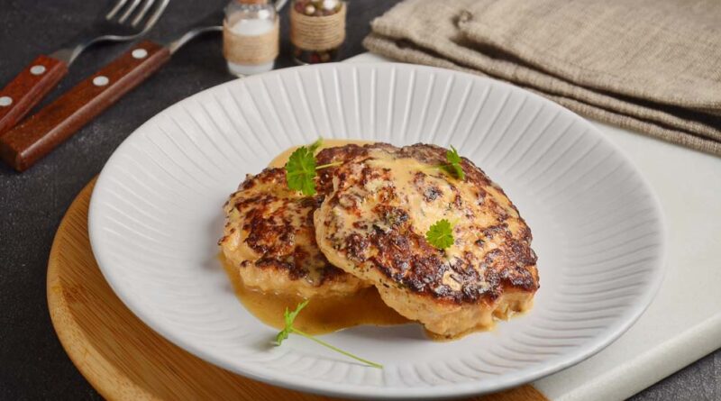 Куриные котлеты в сметане на сковороде лежат на тарелке